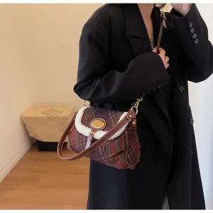 Detail of red and green plaid shoulder bag with white faux fur trim and gold buckle