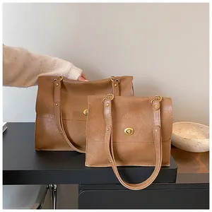 Detail view of retro brown leather tote bag set with golden metal twist lock closure