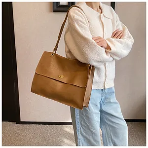 Brown large capacity shoulder bag with pleated faux leather and gold metal clasp on model