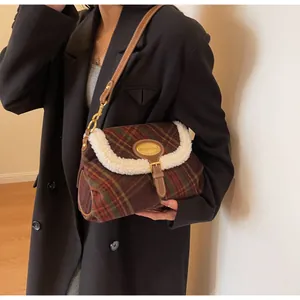 Detail of wool plaid shoulder bag with faux fur trim and gold buckle on a model