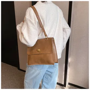 Brown vintage faux leather shoulder bag with metallic clasp shown on a female model