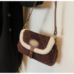 Detail of plaid wool underarm bag with white faux fur trim and vintage metal plaque