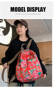 Detail of red floral backpack side pocket and adjustable brown strap on model