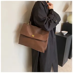 Detail shot of a large vintage brown shoulder bag with a gold turn-lock on a model