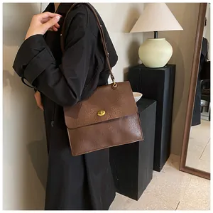 Detail of vintage brown leather shoulder bag featuring a gold twist-lock and textured finish