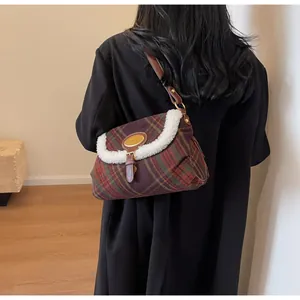 Detail of retro plaid underarm bag with faux fur trim and leather strap on a black coat