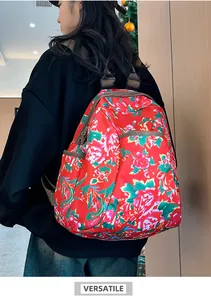Macro detail of red floral backpack showing vibrant peony print and brown nylon straps
