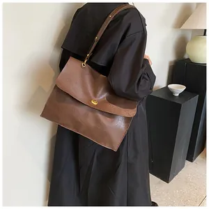 Detail of vintage dark brown messenger bag with gold clasp shown on a model