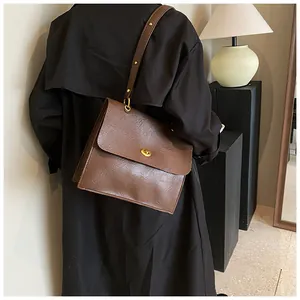 Detail of vintage dark brown faux leather shoulder bag with golden oval twist lock closure