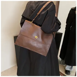 Detail of dark brown tote bag featuring vintage pleated texture and gold metal twist lock