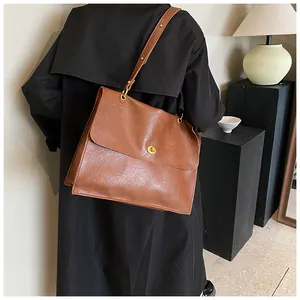 Brown retro shoulder bag with golden rotary lock shown on model in a minimalist studio
