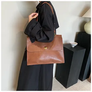 Detail of a large brown leather tote bag with a vintage texture and gold twist lock
