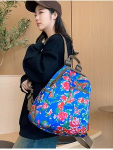 Blue backpack with traditional Chinese floral peony pattern shown on a female model