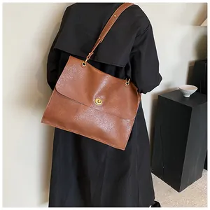 Brown litchi texture tote bag featuring a gold twist lock and a flap closure detail