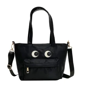 Schwarze Nylon-Beuteltasche mit großen Augen und verstellbarem Riemen auf weißem Hintergrund
