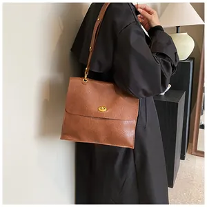 Close-up of vintage brown leather handbag with pleated texture and gold turn-lock closure