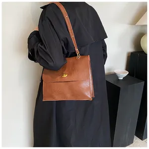 Detail view of vintage brown leather shoulder bag with gold turn-lock and soft texture