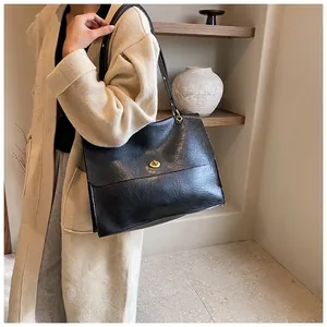 Detail of black wrinkled leather shoulder bag with gold metal clasp on model