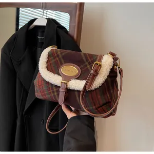 Detail of red and green plaid shoulder bag with soft fleece trim and gold logo plaque