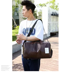 Détail d'un sac de voyage en cuir PU marron avec texture litchi et bandoulière réglable