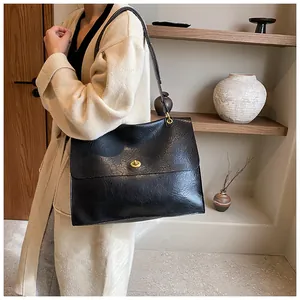 Close-up of black textured leather tote bag featuring a premium gold swivel lock buckle
