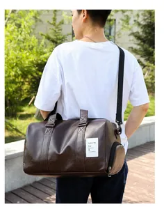Sac de voyage en cuir PU marron avec bandoulière porté par une personne dehors