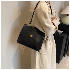 Detail of vintage black oil-wax leather shoulder bag with gold twist-lock on model