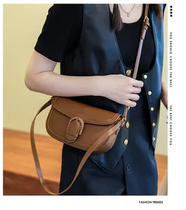 Sacoche selle en cuir marron caramel avec boucle dorée portée par un mannequin