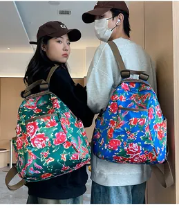 Detailed back view of green and blue floral backpacks with adjustable straps on models