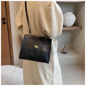 Black vintage leather shoulder bag with gold oval lock worn with a beige tweed coat