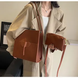 Detail of caramel brown elephant-shaped tote bag and matching pouch on khaki coat