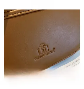 Gros plan du sac en cuir vintage marron montrant les coutures et le logo en relief