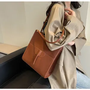 Detail of dark brown matte leather tote bag featuring unique elephant-shaped charm decoration