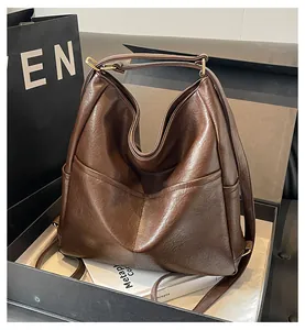Detail of soft brown leather texture and stitching on large capacity tote with gold hardware