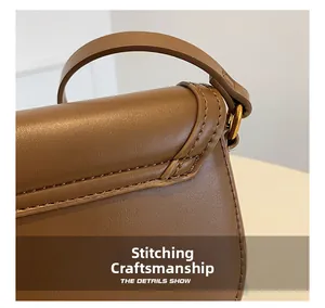 Gros plan sur la couture précise du sac à bandoulière vintage en cuir marron