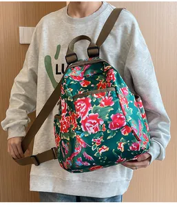 Detail of floral ethnic backpack with red peony and peacock print on green nylon fabric