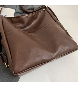 Close-up of vintage dark brown faux leather bag showing soft pleated texture and gold hardware