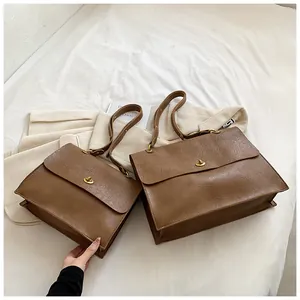 Detail of two vintage brown textured leather handbags with golden turn-lock fasteners