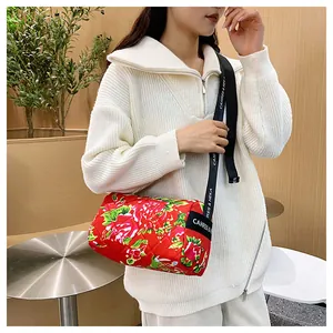 Macro view of red floral quilted cylinder bag with牡丹 peony print and black strap