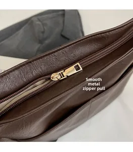 Macro shot of smooth hardware zipper pull on vintage dark brown leather bucket bag