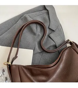 Detail of dark brown hobo bag with gold hardware and textured leather strap