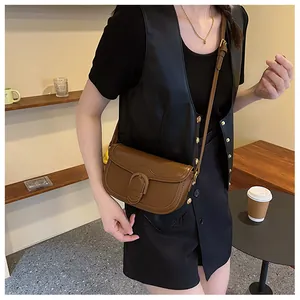 Détail d'un sac besace en cuir marron foncé avec une grande boucle sur la bandoulière