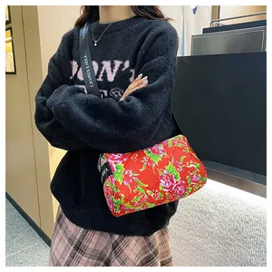Detail of red floral quilted shoulder bag with wide strap and peony pattern