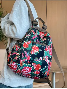 Detail of floral backpack with red roses pattern on black nylon fabric worn by a model