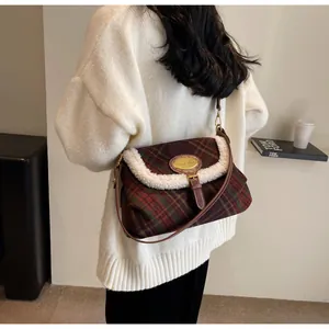 Detail of wool plaid underarm bag with faux shearling trim and brown leather accents