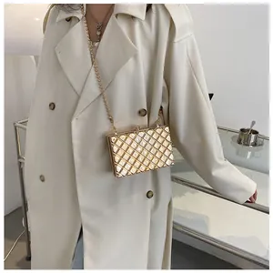 Detail einer goldenen gesteppten Hartschalen-Clutch mit Perlen- und Metallkette