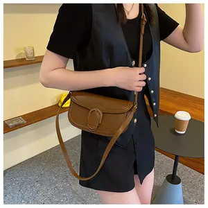 Détail d'un sac besace marron vintage avec texture en cuir mat et boucle en forme de U