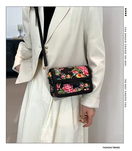 Detail of crossbody bag with vibrant traditional Chinese floral pattern on black leather