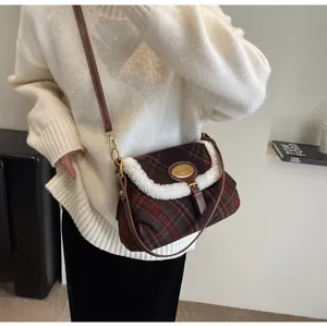 Detail of red and green plaid shoulder bag with white faux fur trim and gold buckle