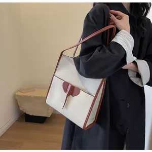 Detail of a minimalist cream tote bag featuring a decorative brown elephant leather patch